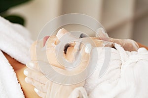 Woman with cotton face mask in beauty salon