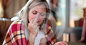 A woman on the couch burns her nose with a spray, close-up