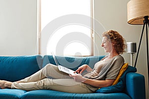 Woman on couch with laptop smiling in apartment
