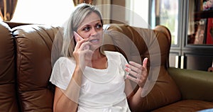 A woman on the couch speaks on a smartphone, close-up
