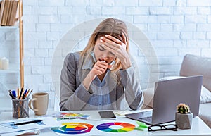 Woman coughs, covered mouth with hand, while working