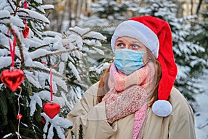 A woman coughs and holds a sore throat at a Christmas tree in winter nature on New Year Eve