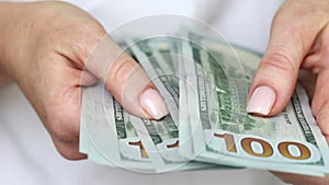 Woman counting 100 US dollar bills in hands, closeup view on banknotes. Business crisis concept.