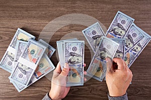 Woman counting American money or 100 USD dollars note at table, business concept