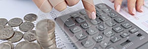 Woman counting on calculator at table with documents and coins closeup