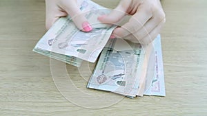 Woman counting cash money, hands in frame. UAE dirhams.