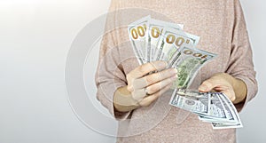 Woman counting dollar bills on greybackground. Counting or spend money