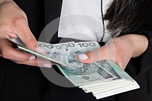 The woman is counting exactly one hundred zlotys paper banknotes