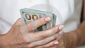 Woman counting US Dollars in hands and pointing the stack towards the camera, closeup