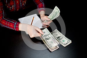 The woman counts the remaining money, distributing the spending