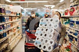 Woman couple with mask and gloves panic buying and hoarding toilette paper in supply store.Pathogen virus pandemic quarantine.