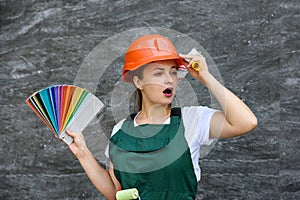 Woman in coverall holding roller and color swatch on abstract background