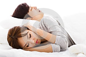 Woman covering ears while husband is snoring