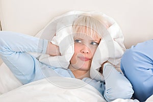 Woman Covering Ears While Sleeping On Bed