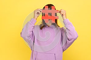 Woman covering face with social media hashtag symbol, recommending to follow trendy content.