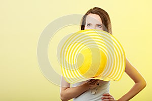 Woman covering face with yellow summer hat.