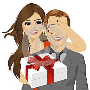 Woman covering her boyfriend's eyes standing behind man with gift