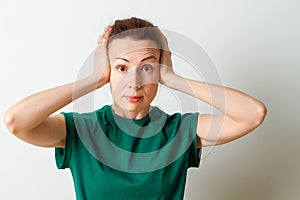 Woman covering her ears isolated on a white background. Looking at camera