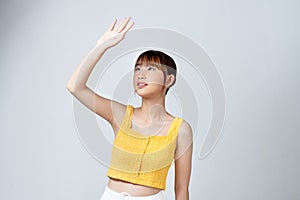 Woman covering her face from sun with her hand while standing against white background