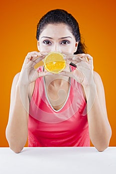 Woman covering her mouth with orange fruit