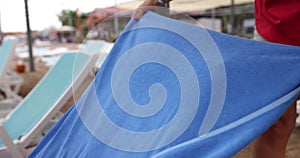 Woman covering sun lounger on sea beach with towel