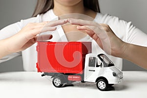 Woman covering toy truck at white table. Logistics and wholesale concept