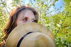 A woman covers her face with a hat in a spring park
