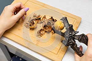 woman cracking walnuts with a hand-held nutcracker.