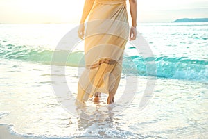 Woman in a cream dress is walking, enjoying the beautiful sunset