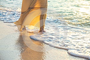 Woman in a cream dress is walking, enjoying the beautiful sunset