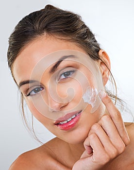Woman, cream on face and skincare for beauty, dermatology with cosmetics product or moisturizer in studio. Portrait