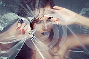 Woman with creative eye makeup peering cellophane