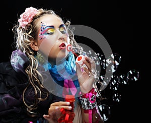 Woman with creative make-up blowing soap bubbles.