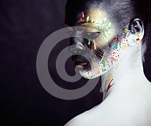 Woman with creative makeup closeup like drops of colors, facepaint close up halloween