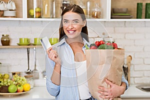 Woman with credit card and bag full of fresh vegetables