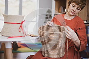 The woman is crocheting from environmentally friendly materials. Jute fiber for home decor. Home hobby of weaving thick-walled rop