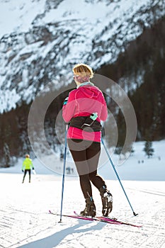 Woman cross country skiing at the foothill of mountain peaks, wide shot