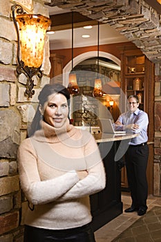 Woman crossing arms with man in background.