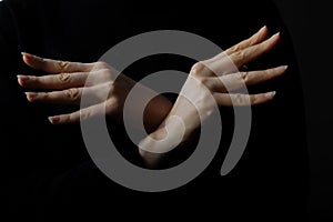 Woman crossing hands forming bird wings isolated on black background