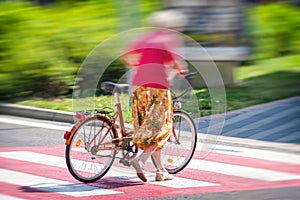 Woman crossing a road on crosswalk with bicycle