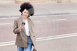 woman crossing the street and checking her mobile