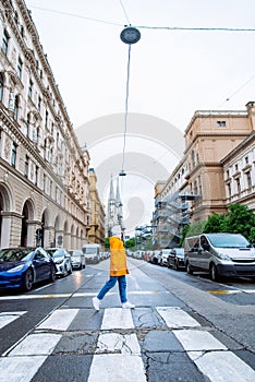 woman crossing street old church towers on background