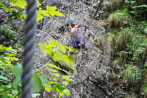 Woman crossing a via ferrata rope bridge in Postalm gorge, Austria. Adventure park concept