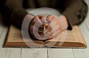 Woman with crucifix in her hands is reading the Bible. Learning the gospel and Catholicism