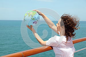 Woman on cruise liner deck holding globe