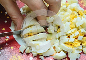 Woman crumbles a boiled egg on a cutting board