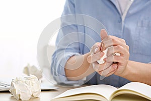 Woman crumpling paper at table. Generating idea