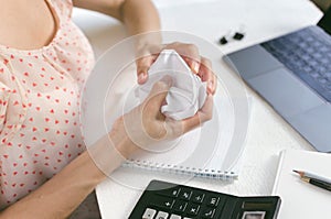 Woman crumpling paper in the workplace in front of a laptop