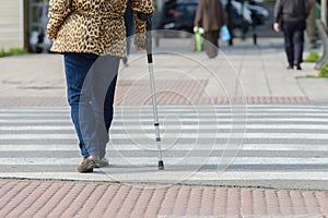 Woman with a crutch at a pedestrian crossing, rear view