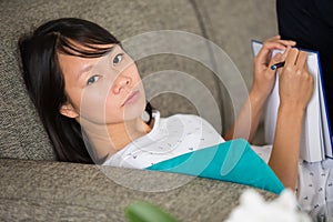 woman crying on sofa while taking notes